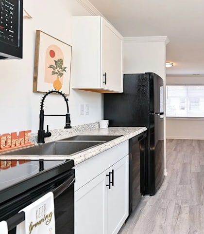A kitchen with black appliances and white cabinets.