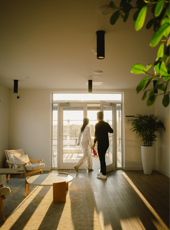A man and a woman are walking through a brightly lit hallway.