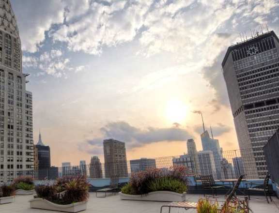 A cityscape with a large building in the foreground and the sun setting in the background.