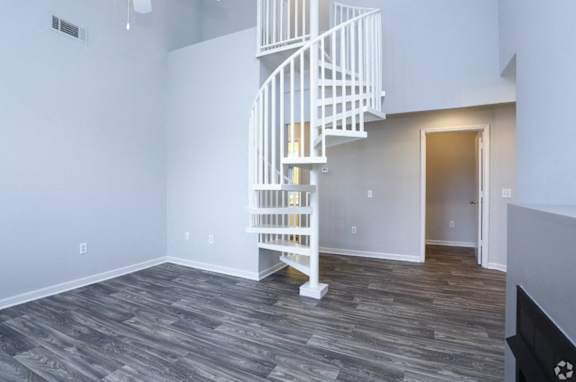 A white spiral staircase in a room with wooden flooring.