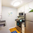A kitchen with a black fridge, wooden floors, and white cabinets.