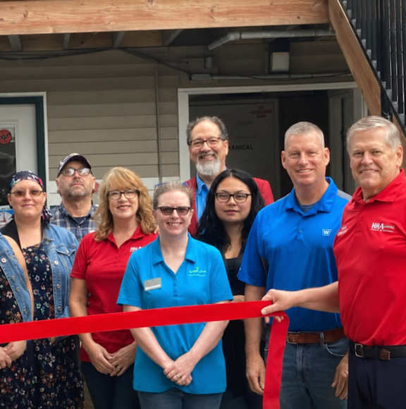 A group of people are gathered for a ribbon cutting ceremony.