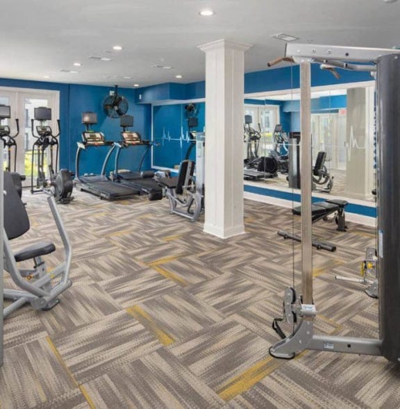 a gym with weights and cardio equipment in a building with blue walls