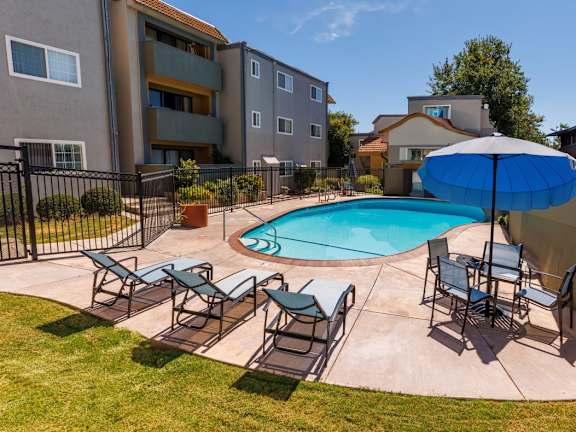 A small pool surrounded by a black fence and chairs.