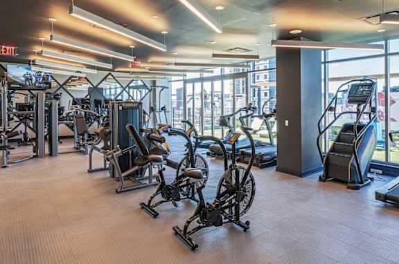 A gym with a variety of exercise equipment including treadmills, stationary bikes, and weight machines.