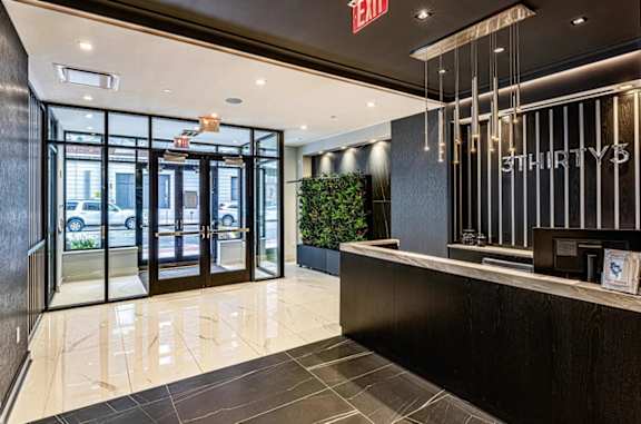 The lobby of a building with a reception desk and glass doors.