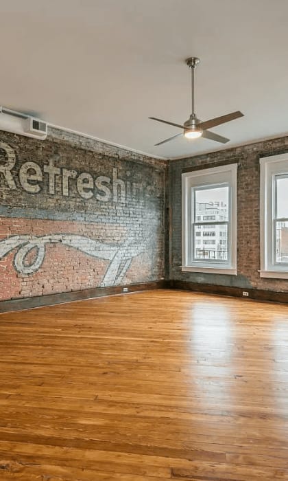 an empty room with wood floors and a brick wall with a mural on it that says and