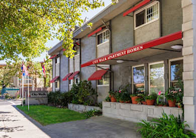 A sign for City Walk Apartment Homes is in front of a building.