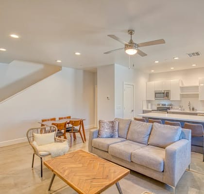 A spacious living room with a couch, chairs, and a dining table.