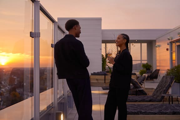 Two people sitting at a table on a balcony during sunset. at Le Columbia Apartments , Gatineau