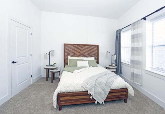 Bedroom model with carpeted floors and white walls, double windows and walk-in closet