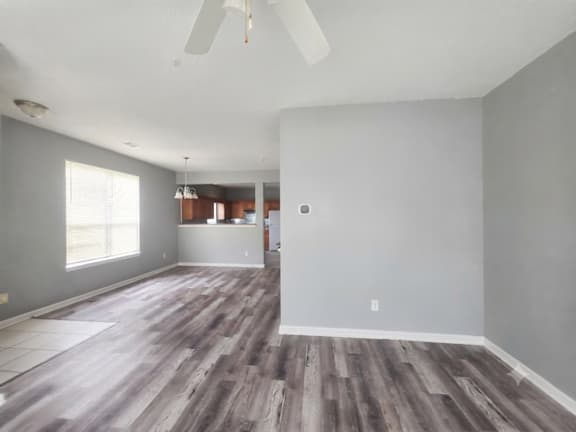 A room with a ceiling fan and wood flooring.