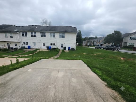 A white building with a grey roof and a concrete driveway in front.