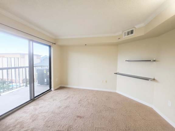 A spacious room with a carpeted floor and a sliding glass door leading to a balcony.