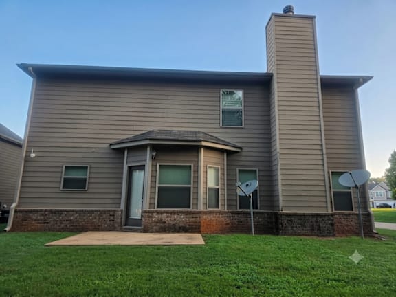 A house with a grey siding and a brick base.