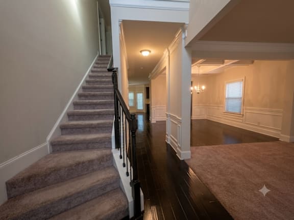 A hallway with a staircase leading to the second floor.