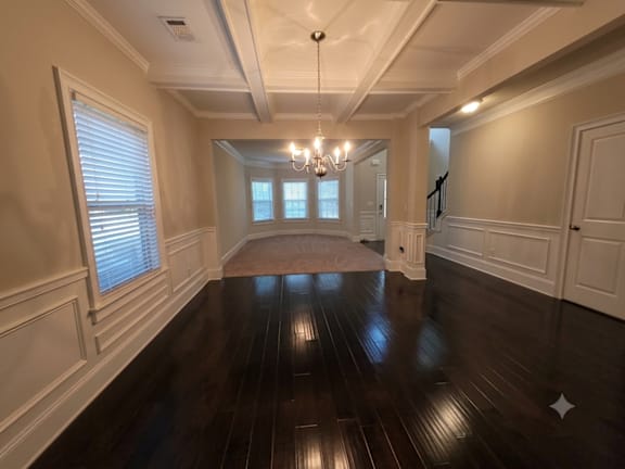 A large, empty room with wooden floors and a chandelier.
