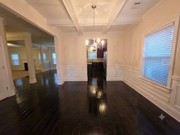 A large, empty room with dark wood floors and white walls.