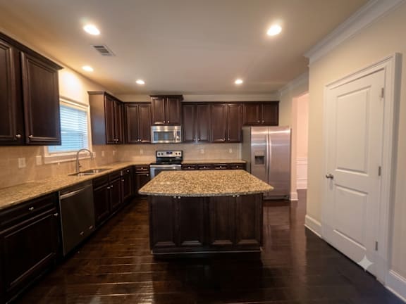A kitchen with dark wood cabinets and a granite countertop.