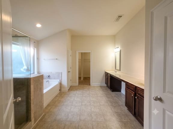 A bathroom with a tub, sink, and mirror.
