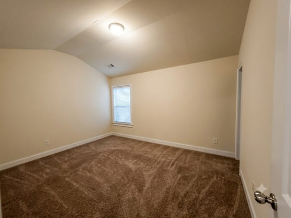 A room with a carpeted floor and a window with blinds.