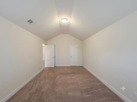 A room with carpeted floor and two doors.