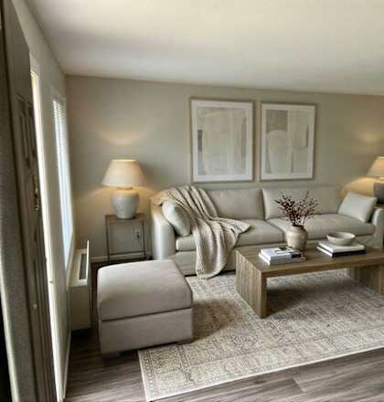 A living room with a grey sofa, a white armchair, a wooden coffee table, and two lamps.