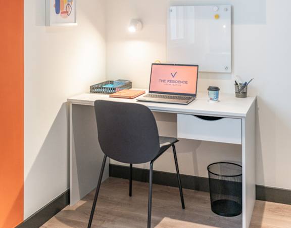 a desk with a laptop and a chair in a room