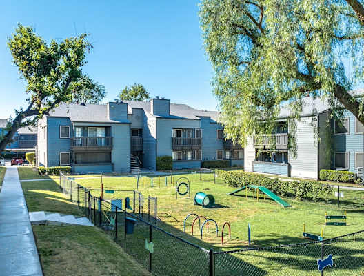 A playground with a swing set and a slide in front of a building.