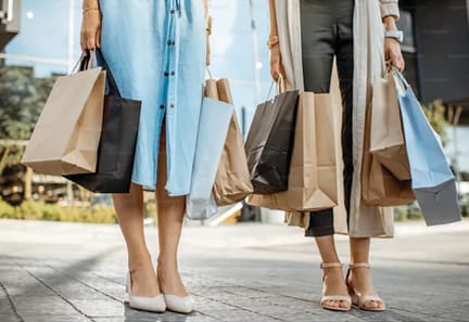 three women holding shopping bags and walking down the street