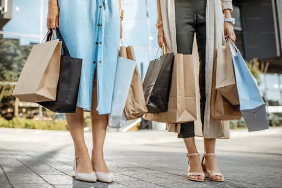 three women holding shopping bags and walking down the street