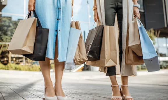three women holding shopping bags and walking down the street