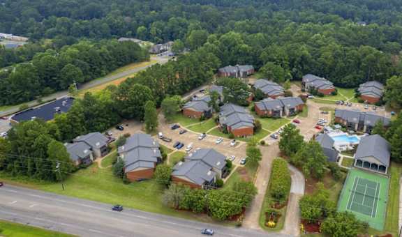 A bird's eye view of a residential area with houses, a tennis court, and a parking lot.