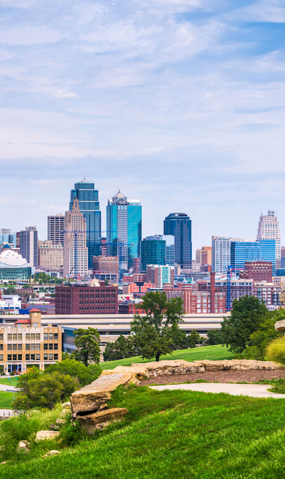 A statue of a man on a horse is in the foreground of a city skyline.