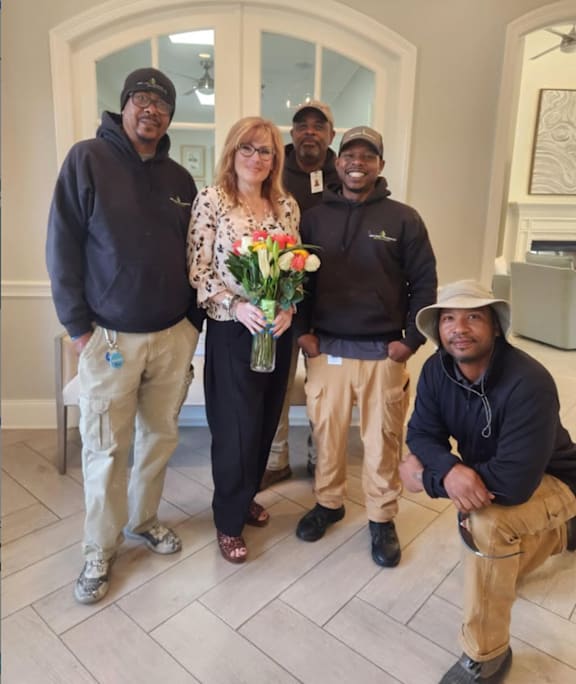 A group of people posing for a photo with a woman holding a bouquet of flowers.