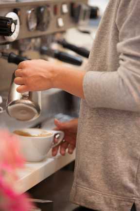 A person is pouring milk into a cup of coffee.