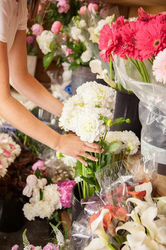 A person is arranging a bouquet of white flowers.