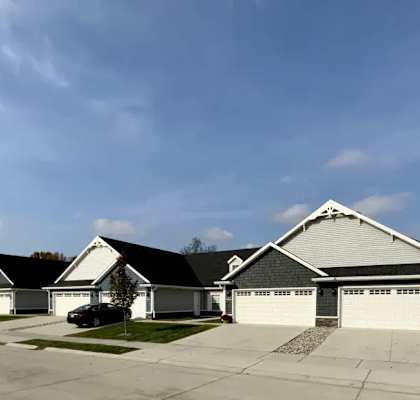 A row of houses with a car parked in front of the first one.