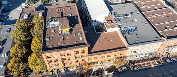 A large building with a red roof is surrounded by other buildings and trees.