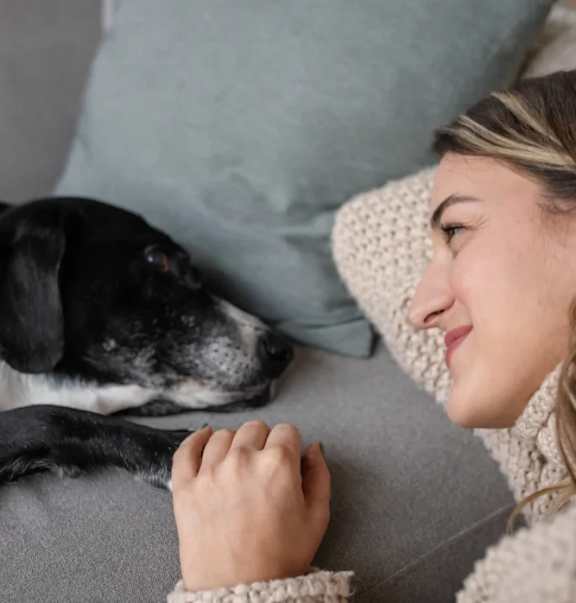 A woman is lying on a couch with her dog.