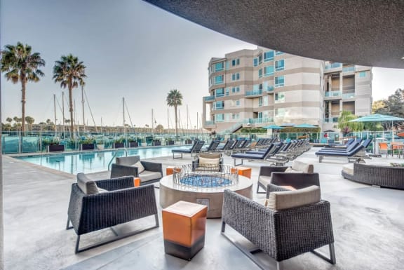 a resort pool with lounge chairs and a poolside table at Esprit Apartments, Marina del Rey, CA