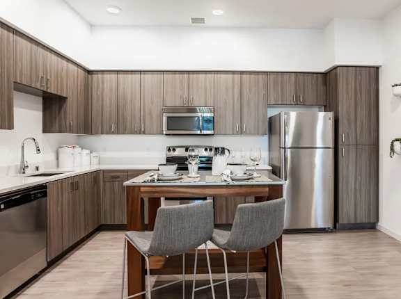 A modern kitchen with a dining table and two grey chairs.