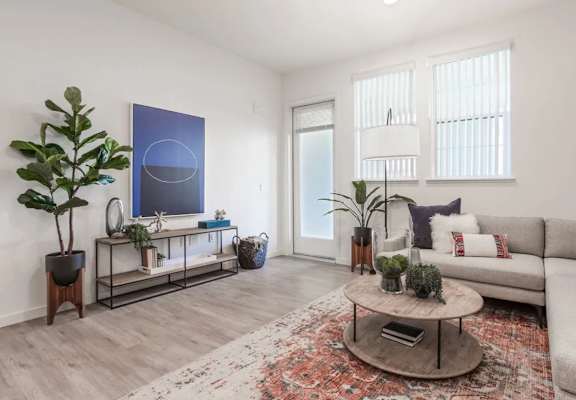 A living room with a grey couch, a coffee table, and a large painting on the wall.