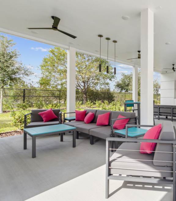 A patio with a table and chairs with a fan in the background.