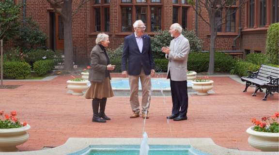 Three people standing in front of a fountain.