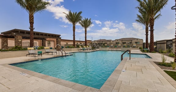A large swimming pool surrounded by palm trees and a tiled patio at Pillar Lago, Peoria, AZ