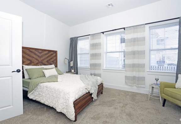 bedroom with 3 windows, carpeted floors and seating area