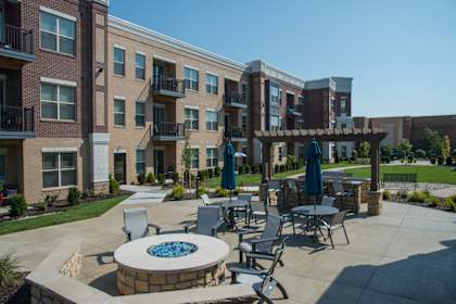 a patio with tables and chairs in front of an apartment building  at The Grandstone, Mason, 45040