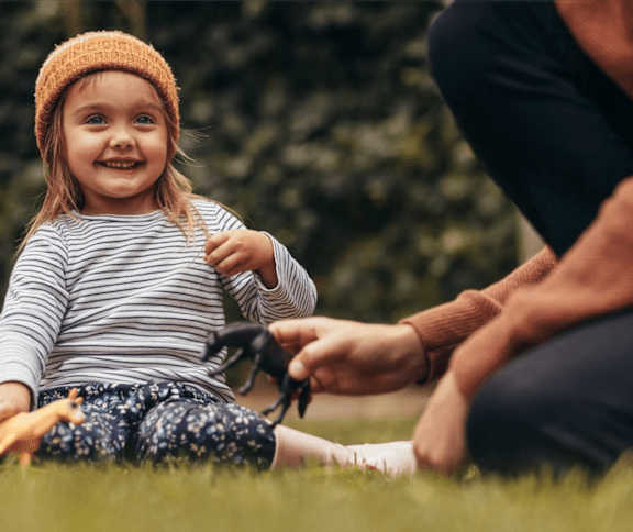 a little girl sitting on the grass next to her parent at Assembly Park Apartments,Telford, TELFORD WREKIN TF1 3LE