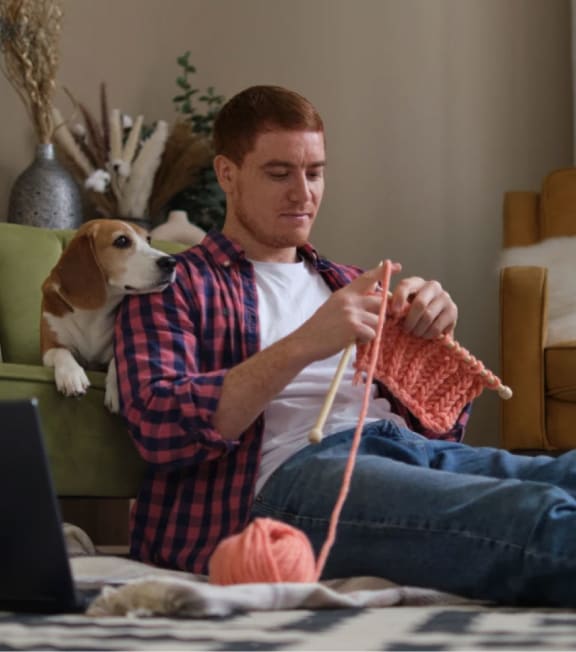a man sitting on the floor with a dog and a laptop